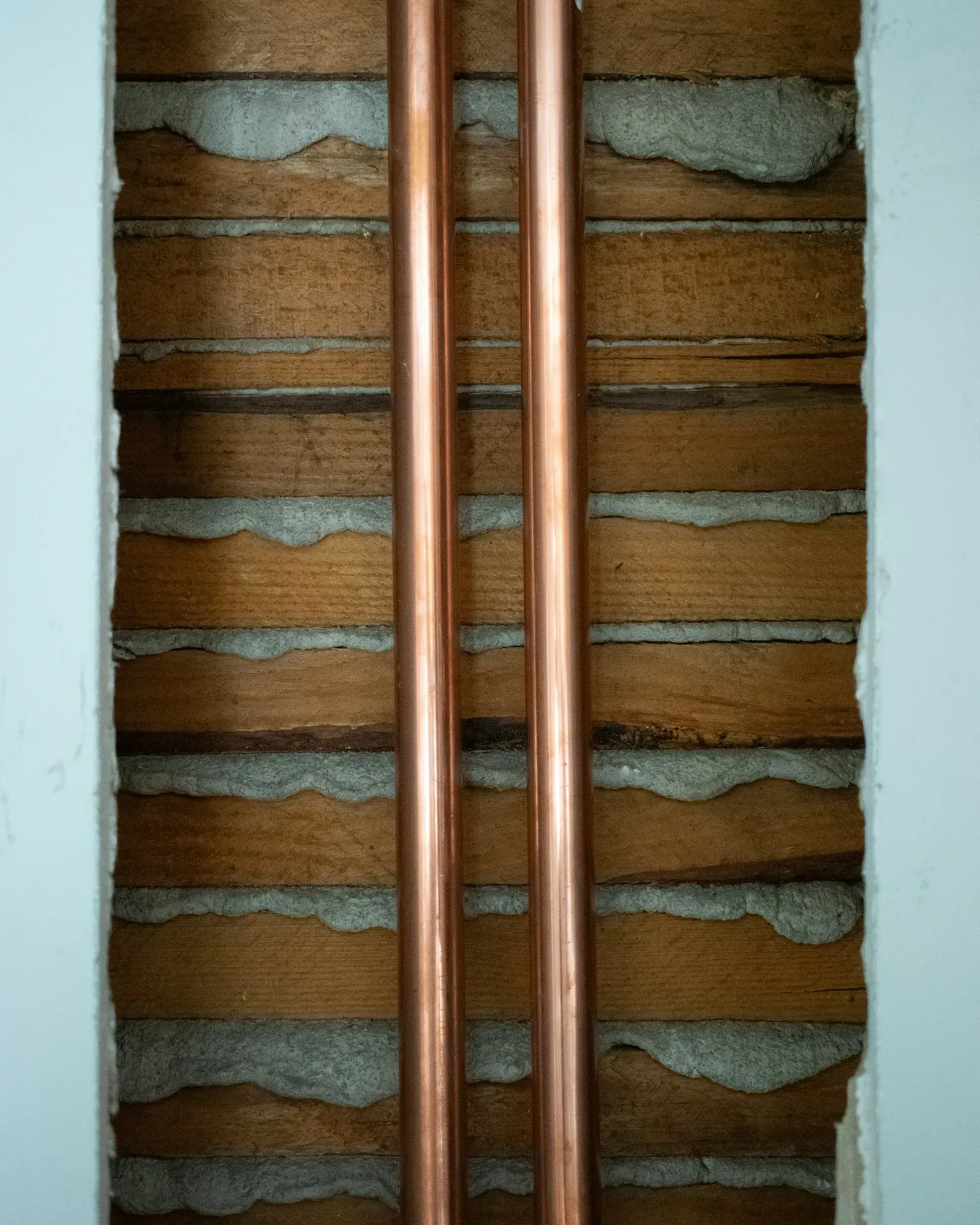 Copper pipes running along a brick wall