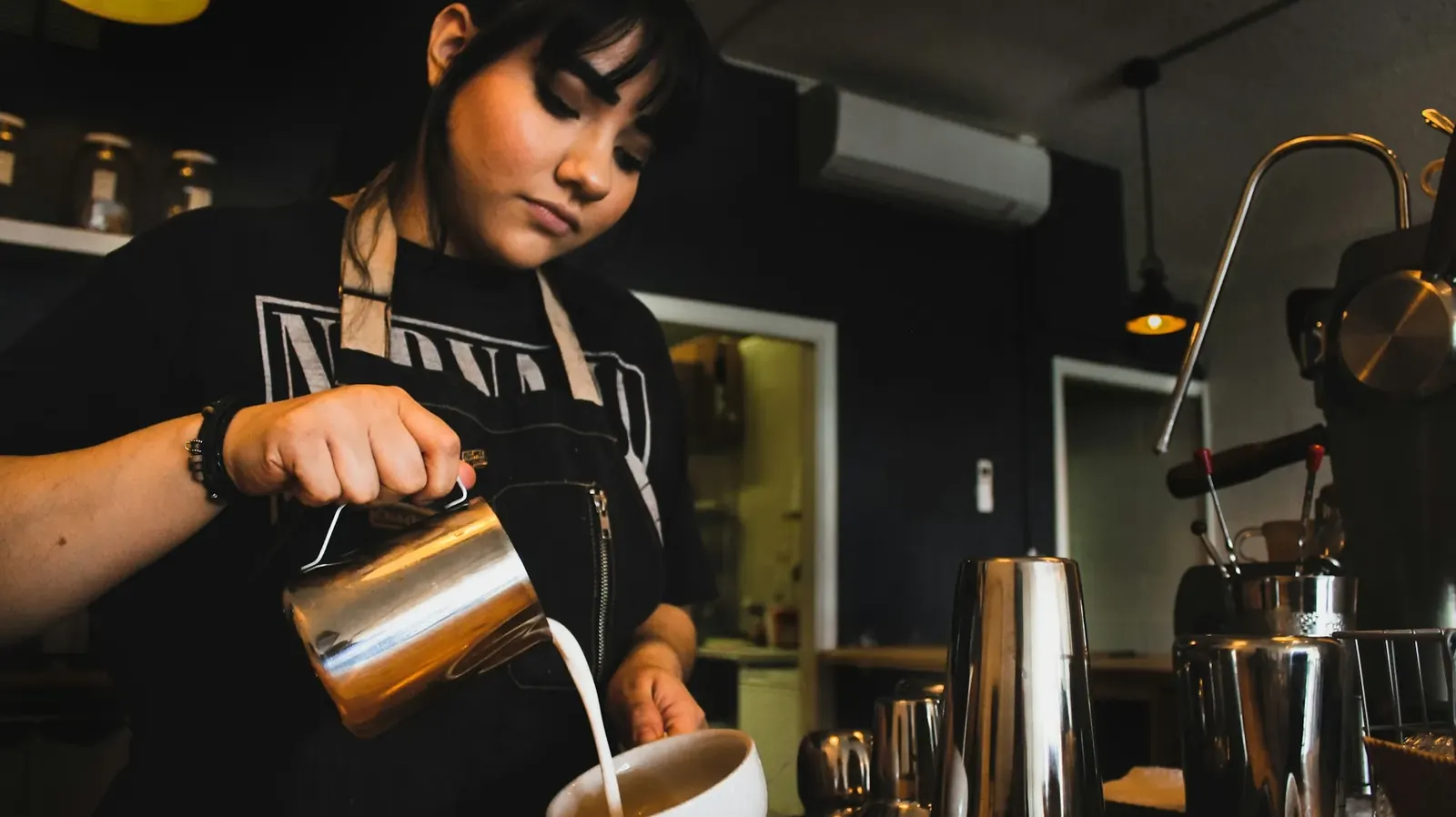 Barista pouring milk in a busy cafe