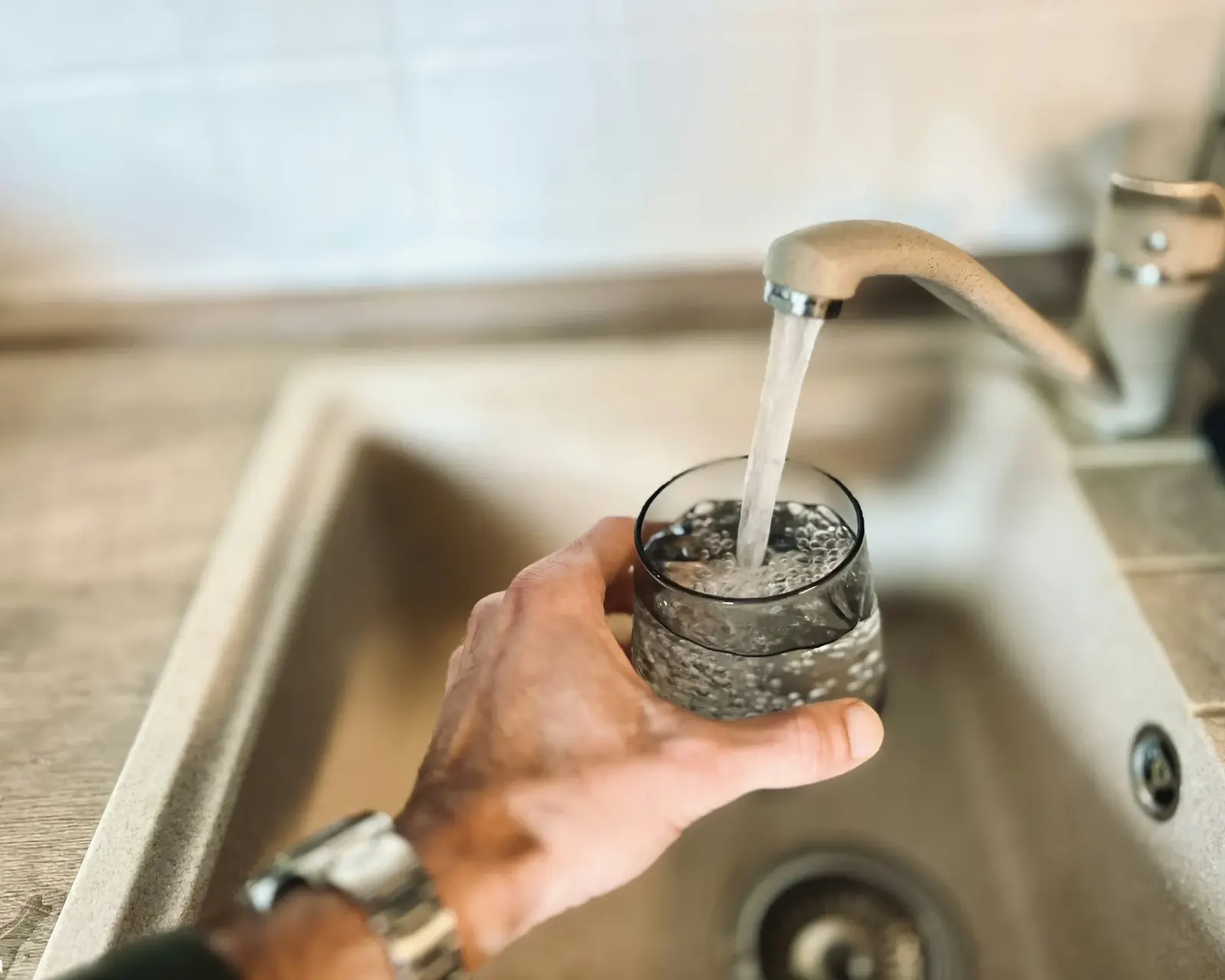 Glass of water held under a kitchen tap