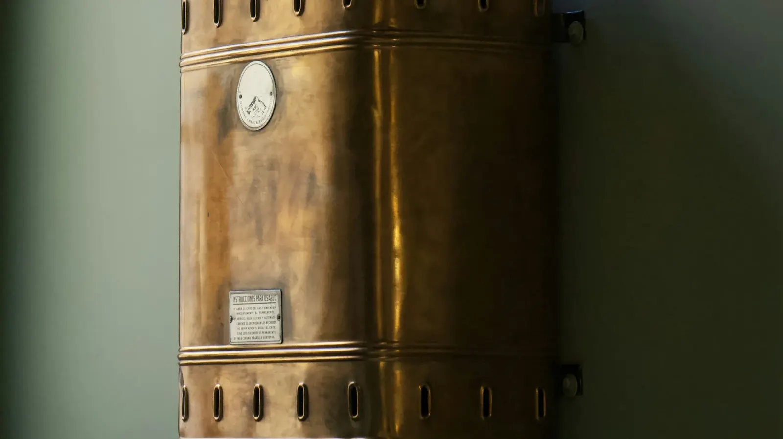 Older copper water heater mounted on a wall